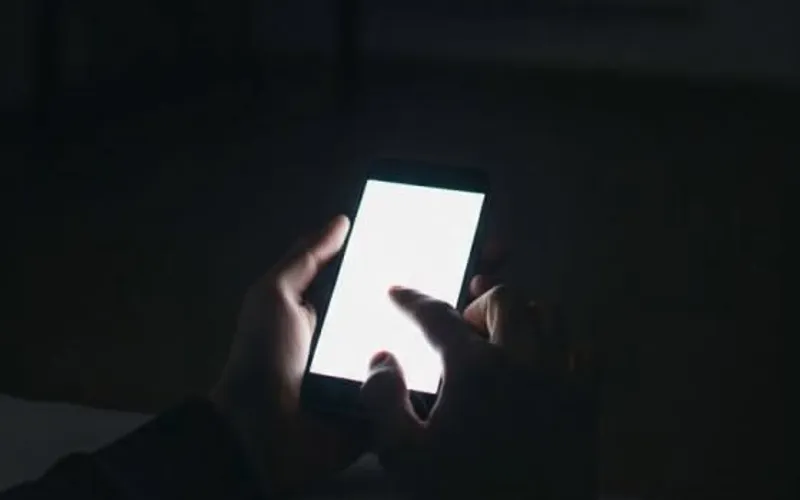 Руки держат телефон с уведомлениями в тёмной комнате